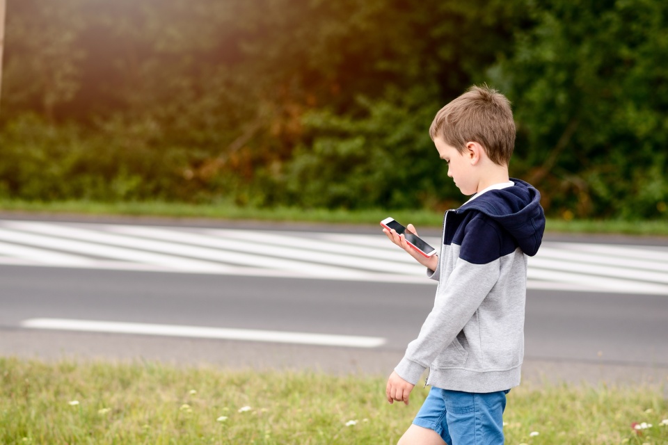 child playing mobile games on smartphone on the street